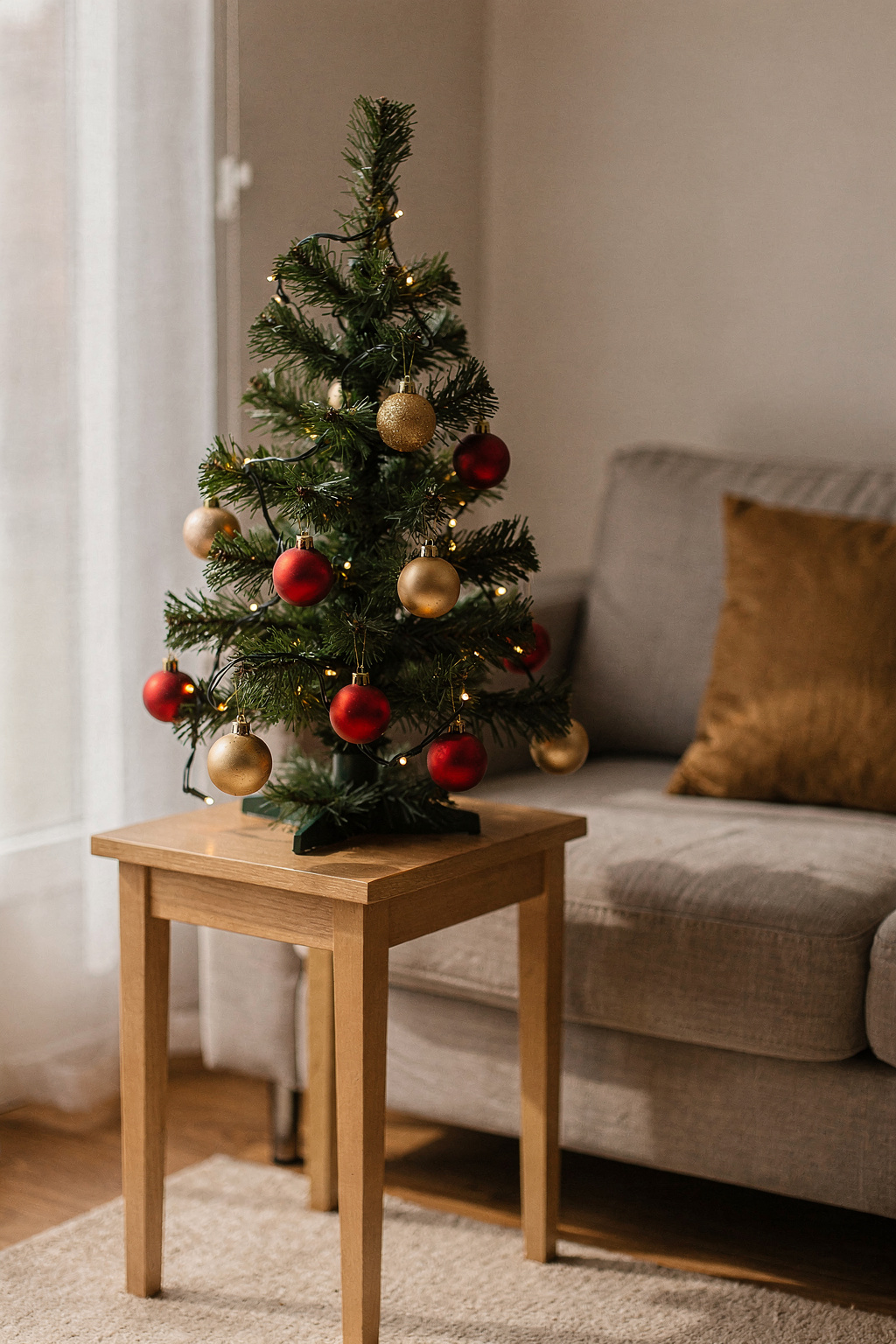 Kleiner Tischbaum auf einem Beistelltisch im Mini Wohnzimmer, dekoriert mit Lichterkette.