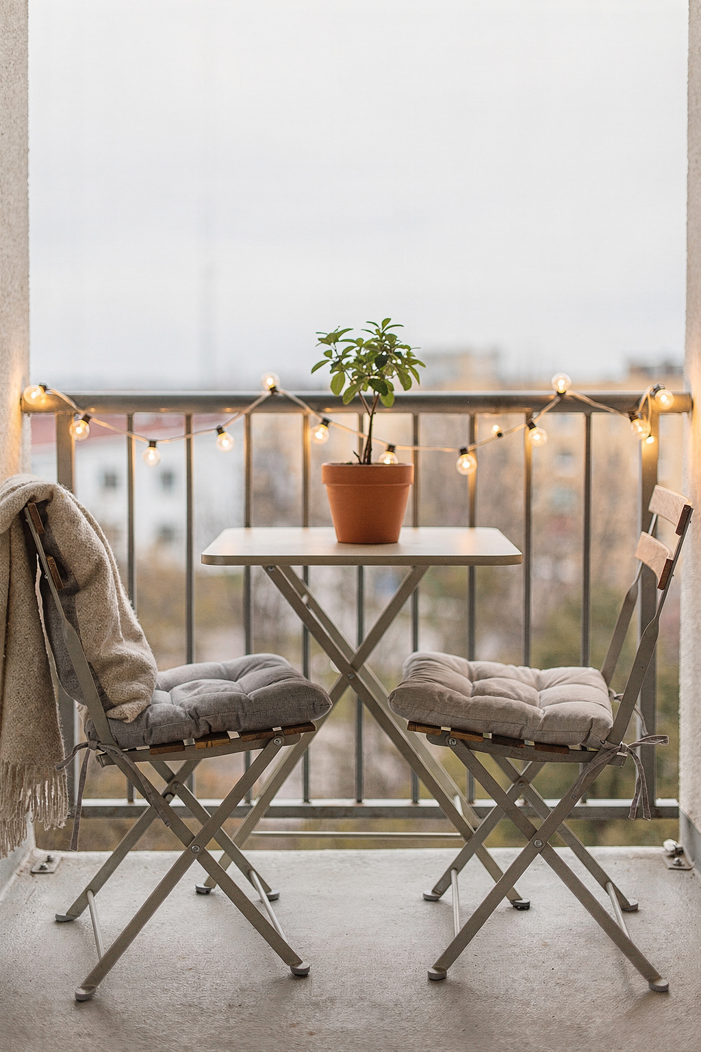 Schmaler Balkon mit platzsparenden Klappmöbeln und Lichterkette als gemütliche Outdoor Lounge.