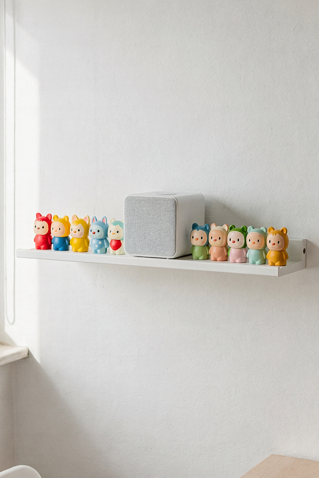 Ein weißes IKEA Wandregal dient als Tonie Regal, mit bunten Tonies Figuren ordentlich aufgereiht im Kinderzimmer.