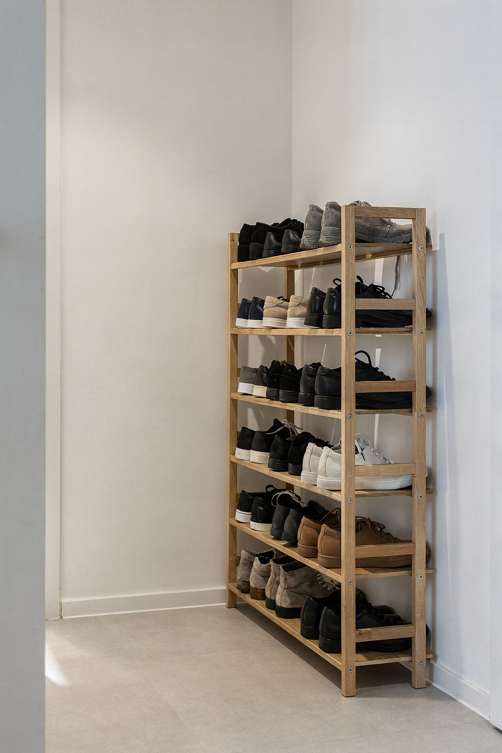 Schmales Schuhregal im Flur mit sortierten Schuhen auf mehreren Ebenen.