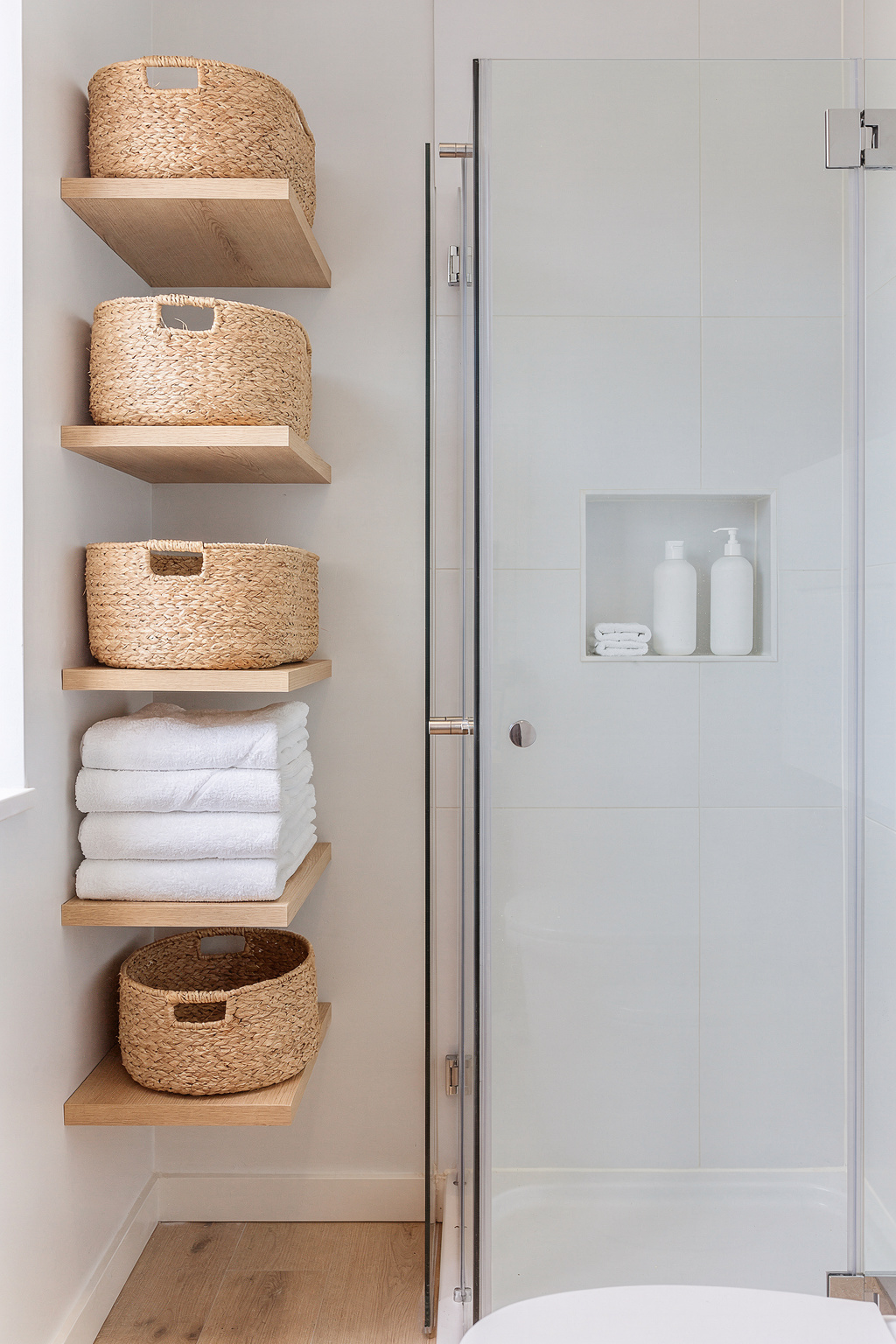 Schmales Bad mit wandhängenden Regalen und Körben zur Aufbewahrung neben der Dusche.