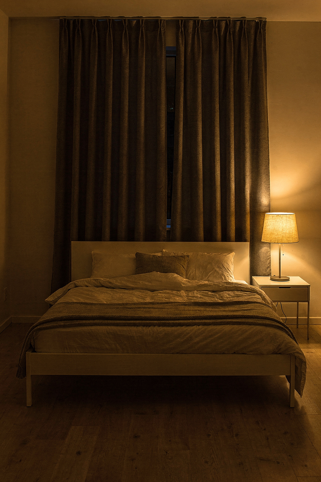 Ein Bett vor dem Fenster mit Verdunkelungsvorhängen zeigt, wie Licht beim Schlafen effektiv blockiert werden kann.