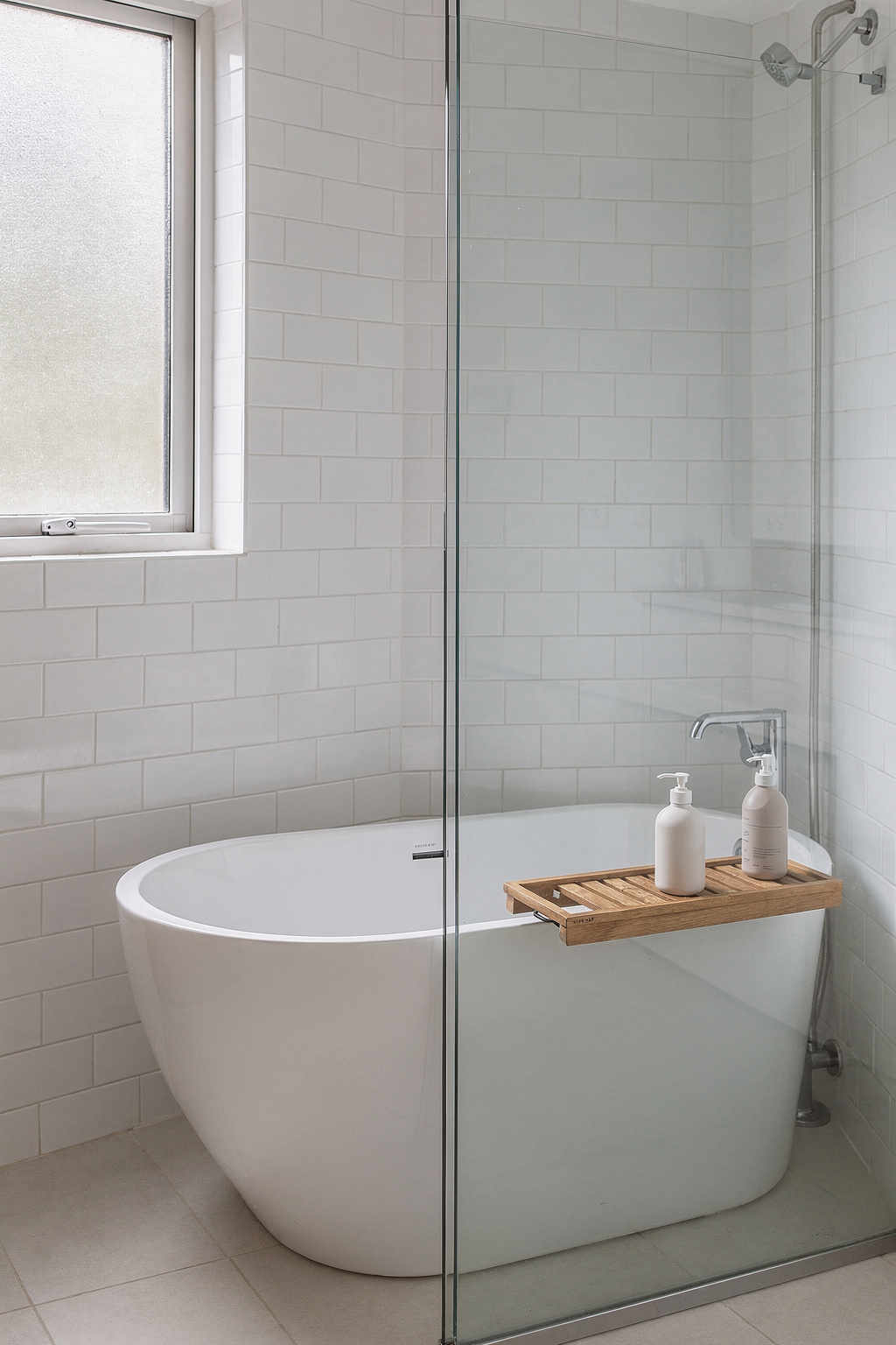 Kleines Bad mit freistehender Badewanne und Dusche, getrennt durch eine Glastrennwand.