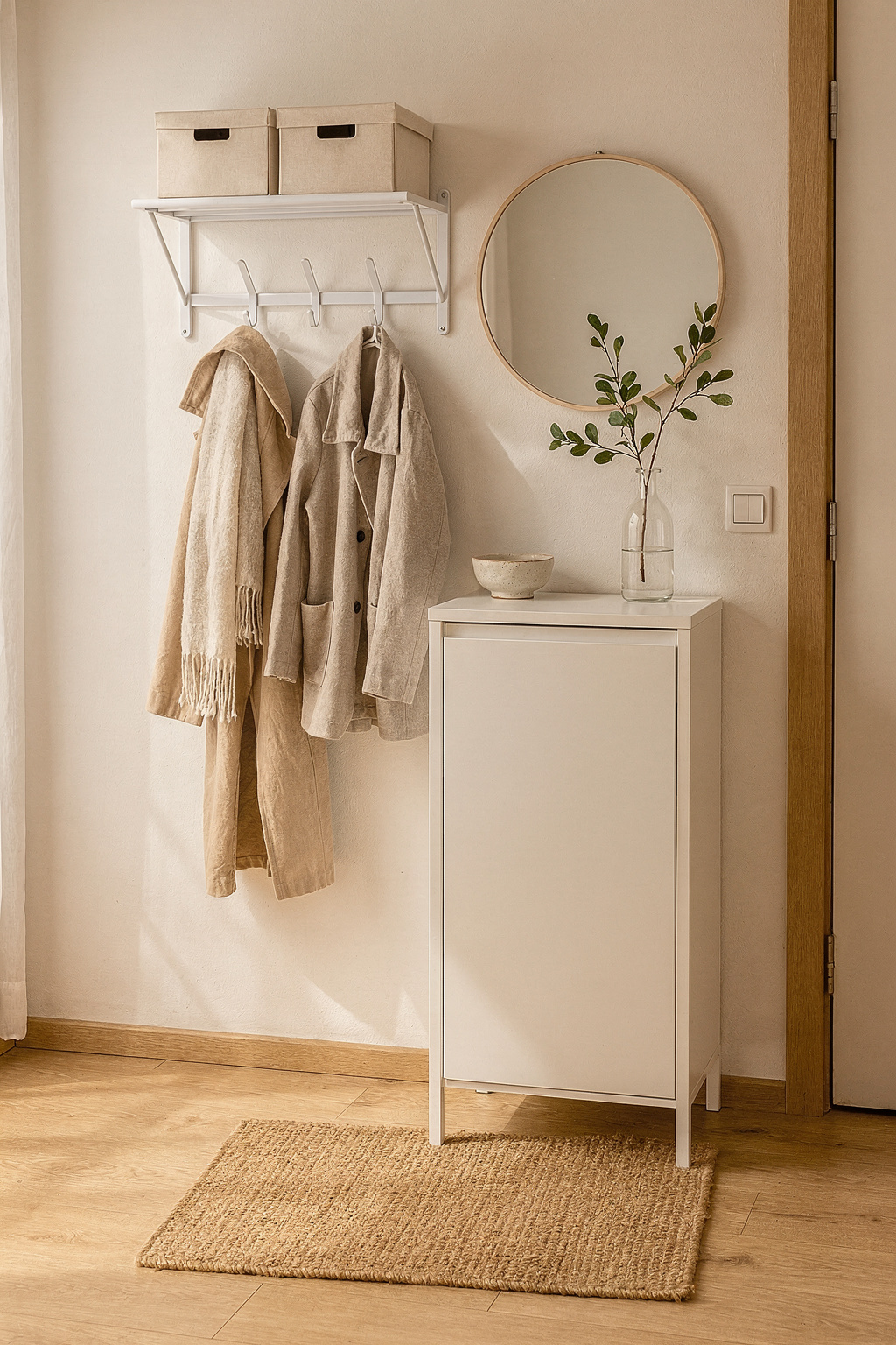 Schmaler Eingangsbereich mit wandmontierter Garderobe, Spiegel und Schuhschrank in einer kleinen Erstwohnung.