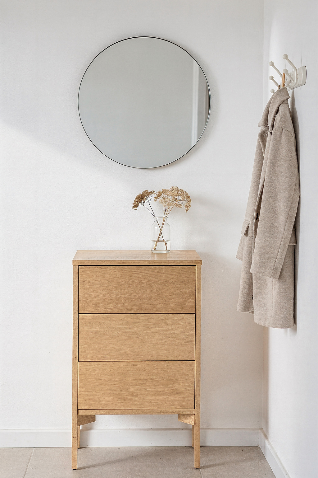 Enge Diele mit heller schmaler Kommode und Spiegel an der Wand.