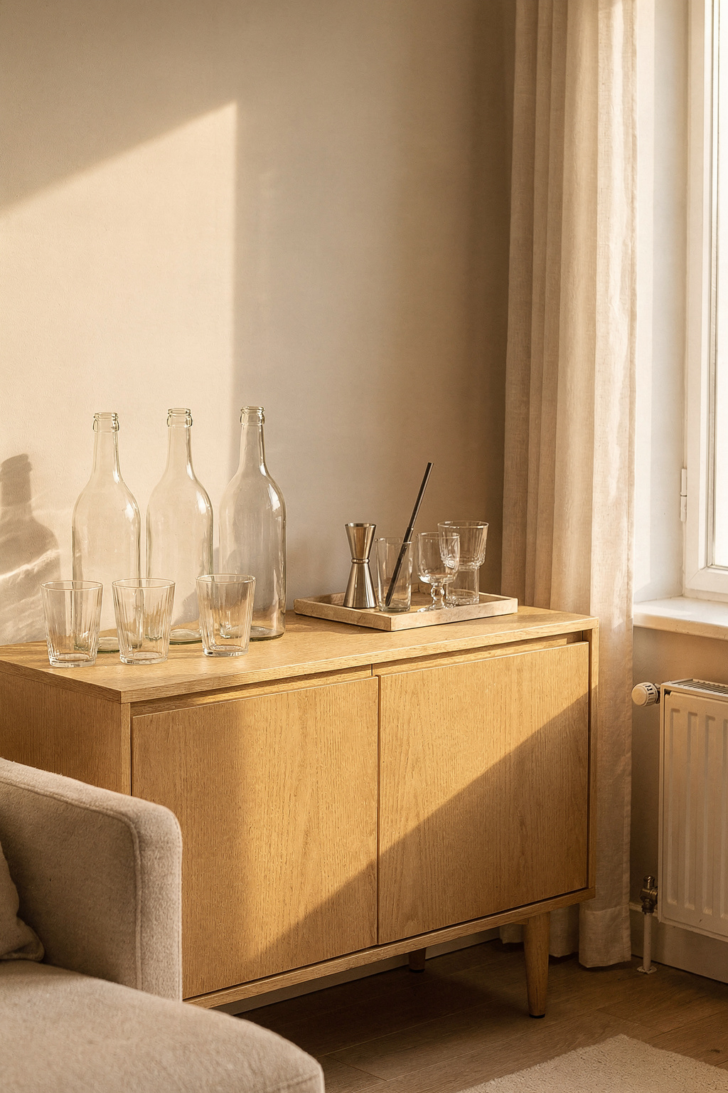 Ein schmales Sideboard als Hausbar im Wohnzimmer mit unlabeled Flaschen, Gläsern und dekorativen Accessoires.