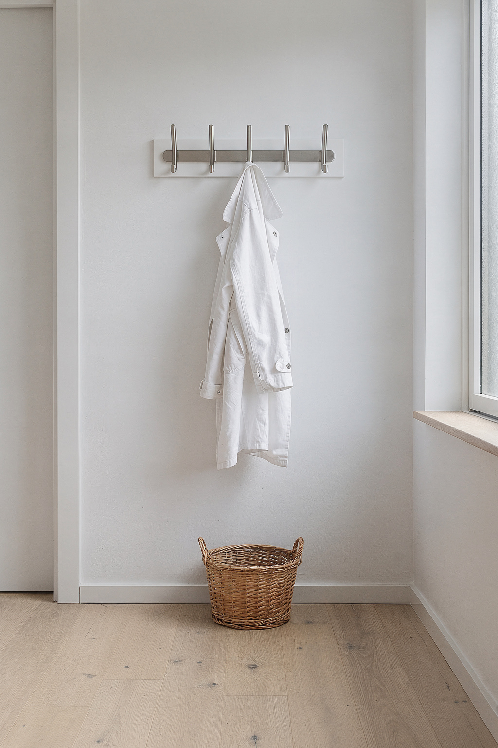 Weißer Flur mit wandmontierter Garderobe und Haken. Heller Dielenboden und minimalistisches Skandinavisches Design.