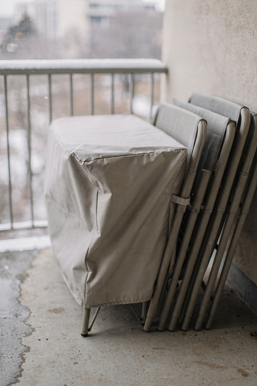 Balkonmöbel werden zum Winterschutz in eine Schutzabdeckung gehüllt und ordentlich auf dem Balkon gestapelt.