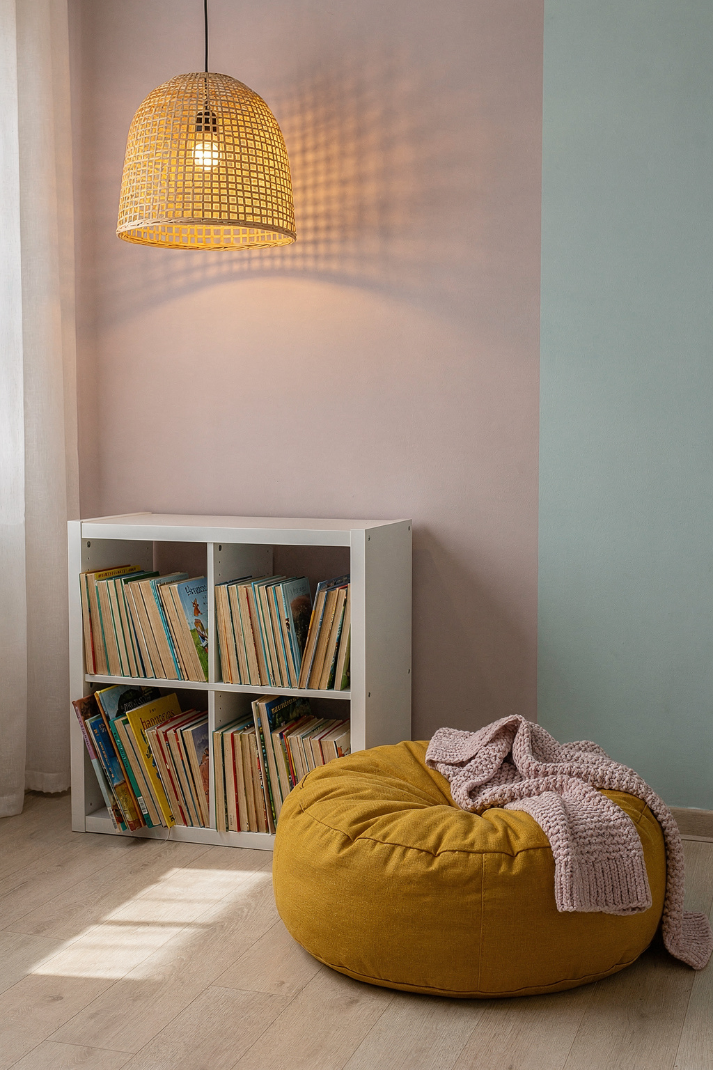 Eine Leseecke im Kinderzimmer mit einem kleinen Regal, Kissen und weiches Licht von einer Hängelampe.
