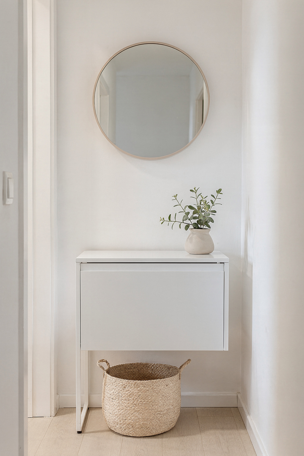 Ein schmales weißes Sideboard im Flur mit Spiegel und Topfpflanze, skandinavischer Einrichtungsstil.