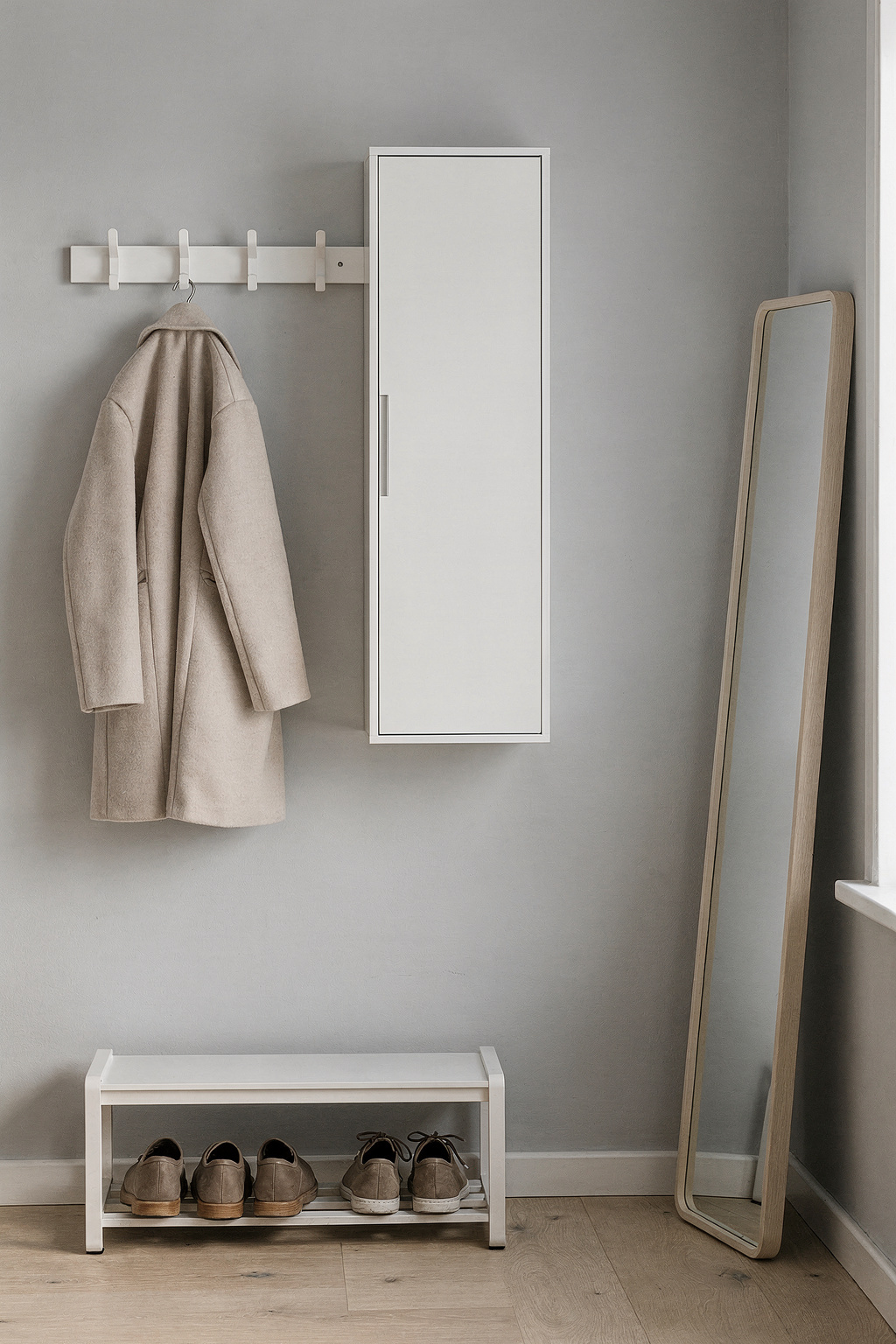 Ein schmaler Flur mit wandmontierter Garderobe, Schuhregal und Spiegel in heller Einrichtung.
