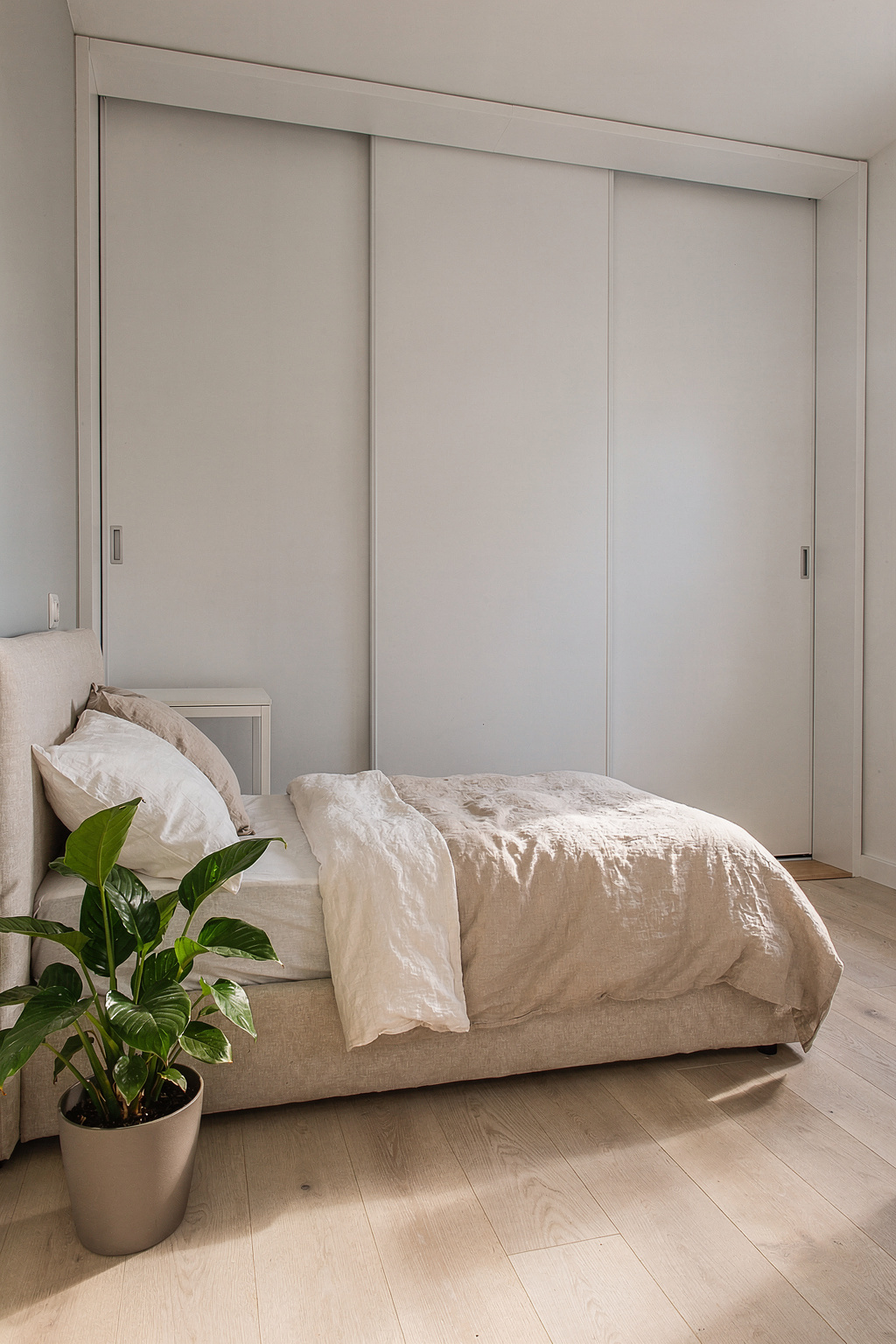 Ein weißer IKEA PAX Kleiderschrank in einem kleinen Schlafzimmer mit platzsparender Einrichtung.