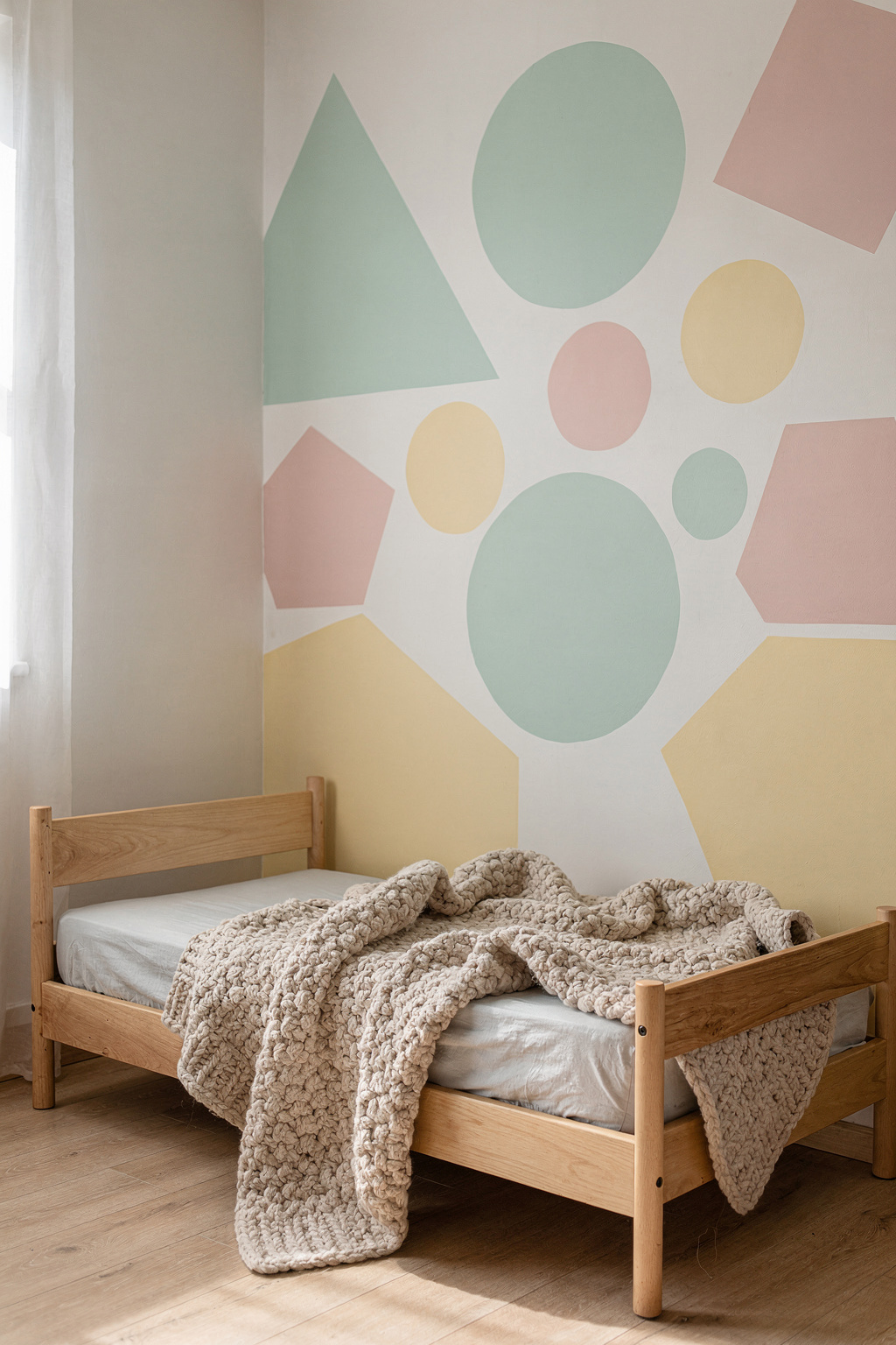 Eine Kinderzimmerwand mit bunten geometrischen Formen in Pastelltönen, bemalt mit Schablonen.