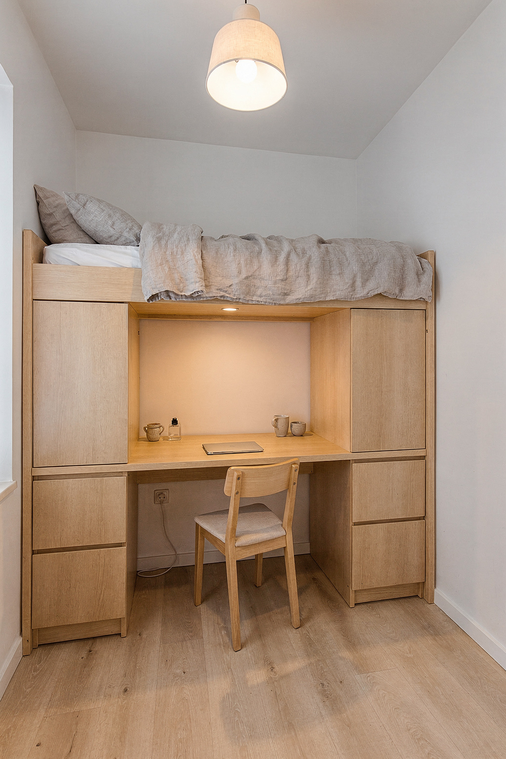 Ein kleines Schlafzimmer mit einem Bett an der Wand und einem platzsparenden Hochbett mit Schreibtisch darunter.