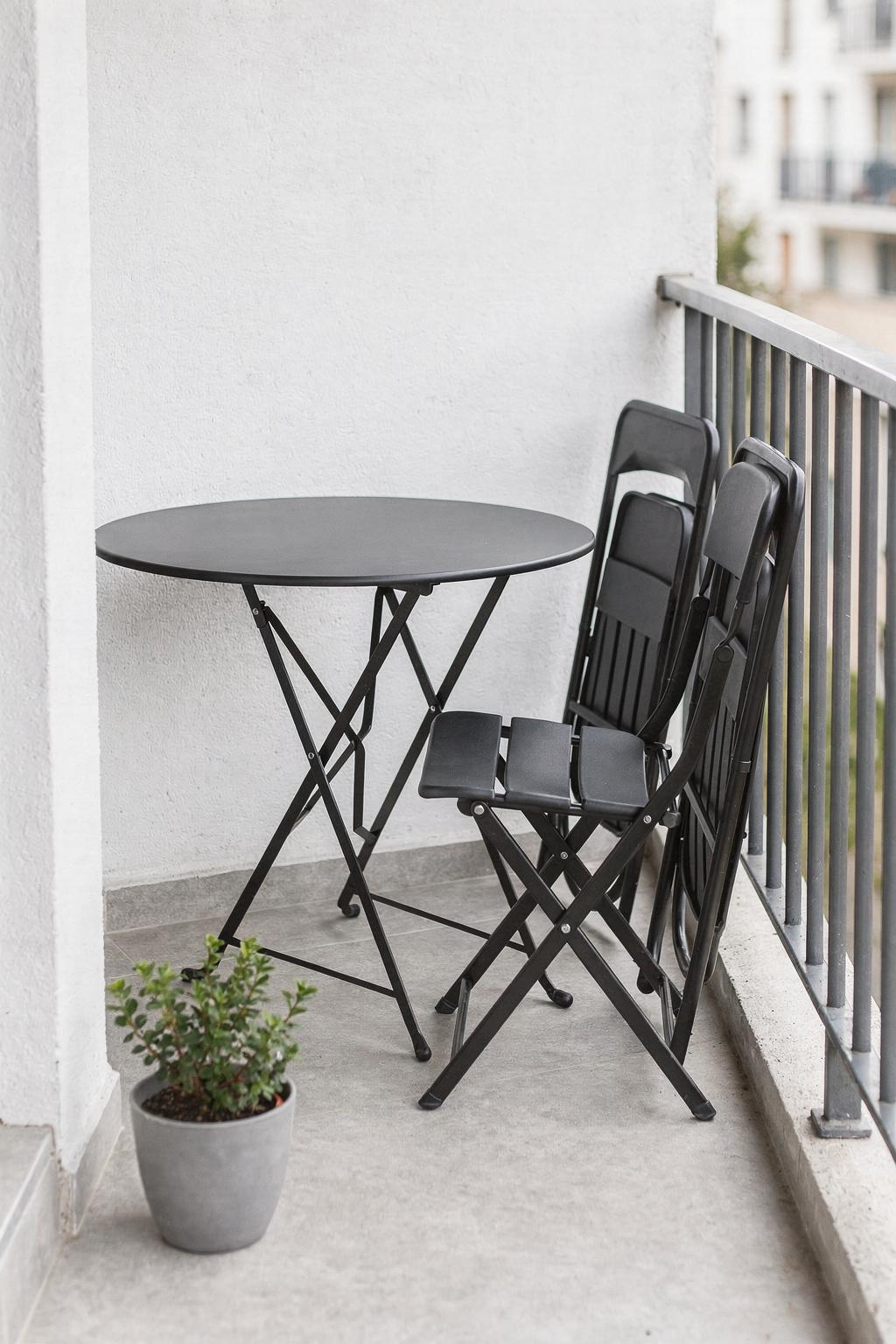 Schmaler Balkon mit einem faltbaren Balkonmöbel Set aus Metall, platzsparend an der Wand angelehnt.