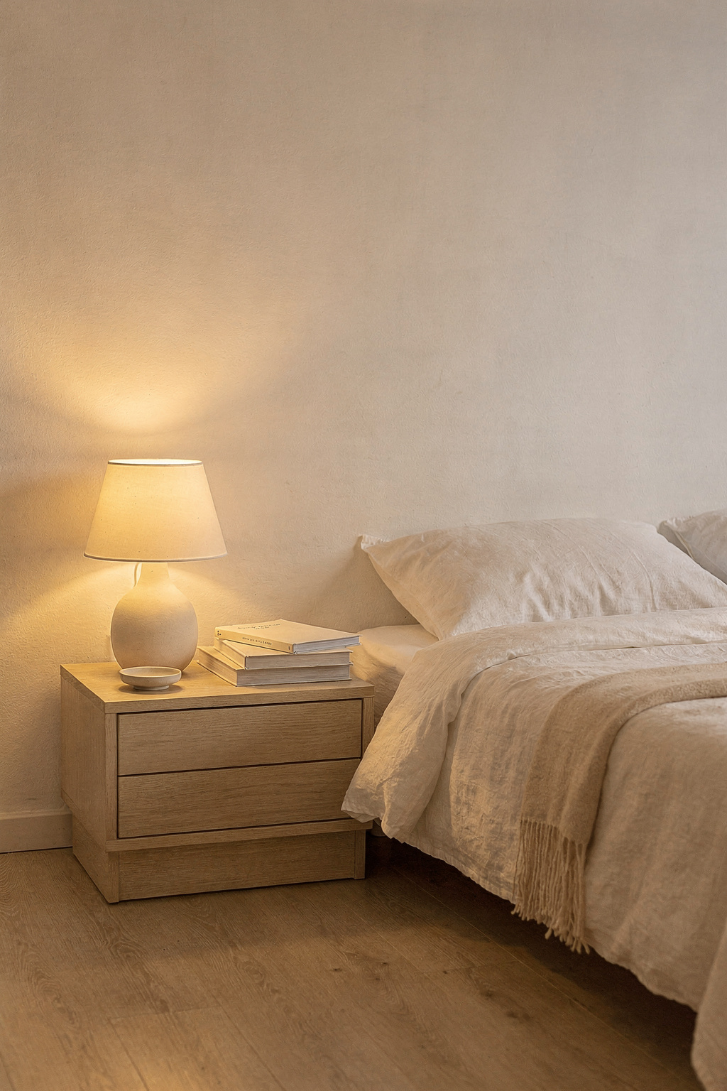 Ein kleines Schlafzimmer mit cleverer Beleuchtung durch eine Nachttischlampe und warmem Lichtschein.