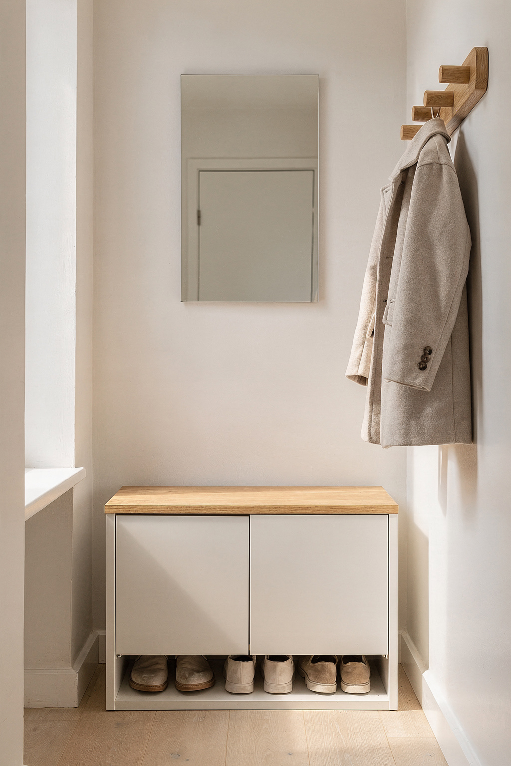 Ein kompaktes Garderoben-Set im kleinen Flur einer ersten Wohnung mit Kleiderhaken, Schuhbank und Spiegel.